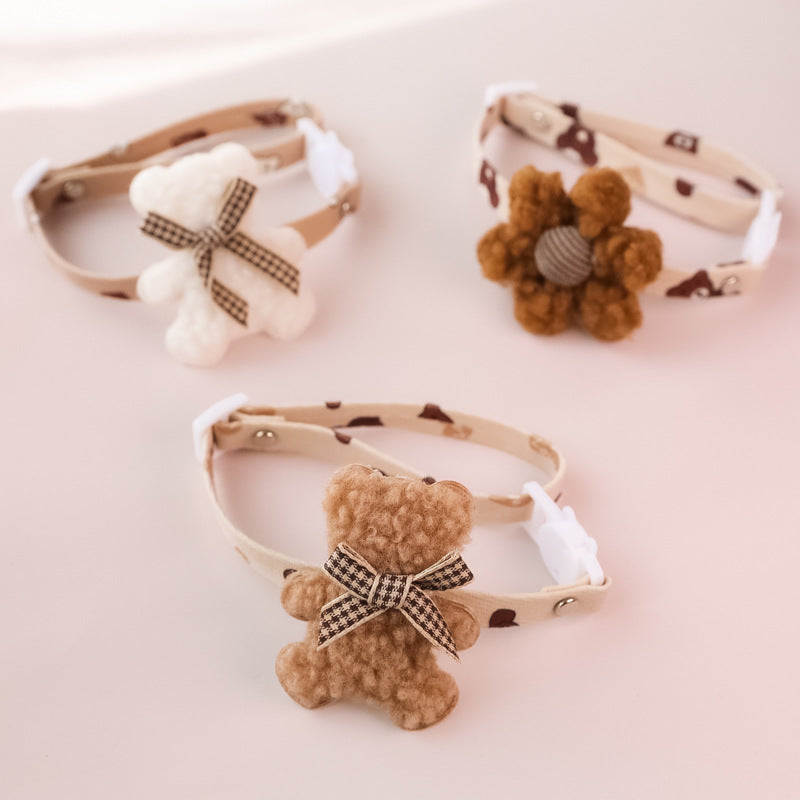Decorative pet collars featuring teddy bear and flower designs on beige strap