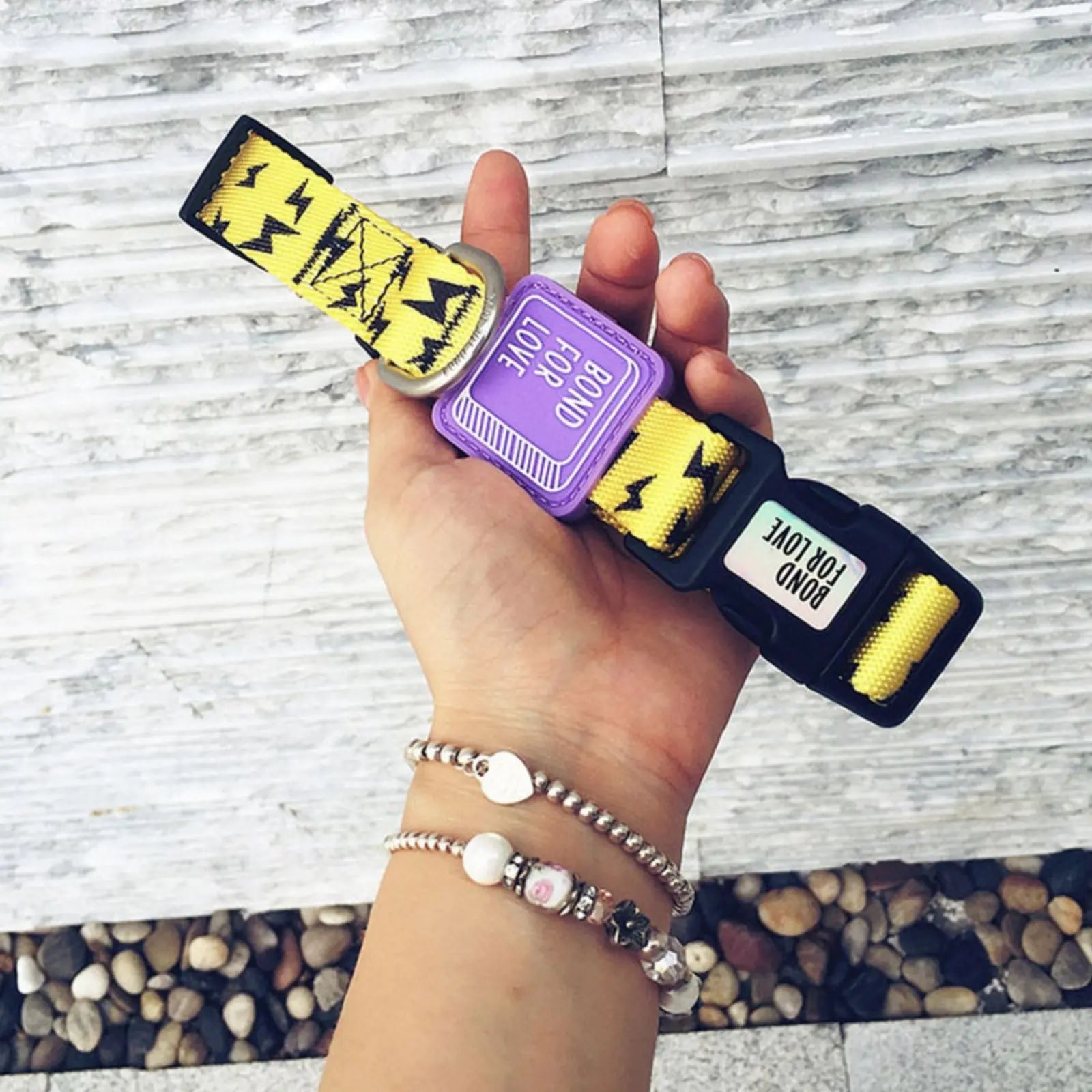 Hand holding printed yellow nylon dog collar with buckle