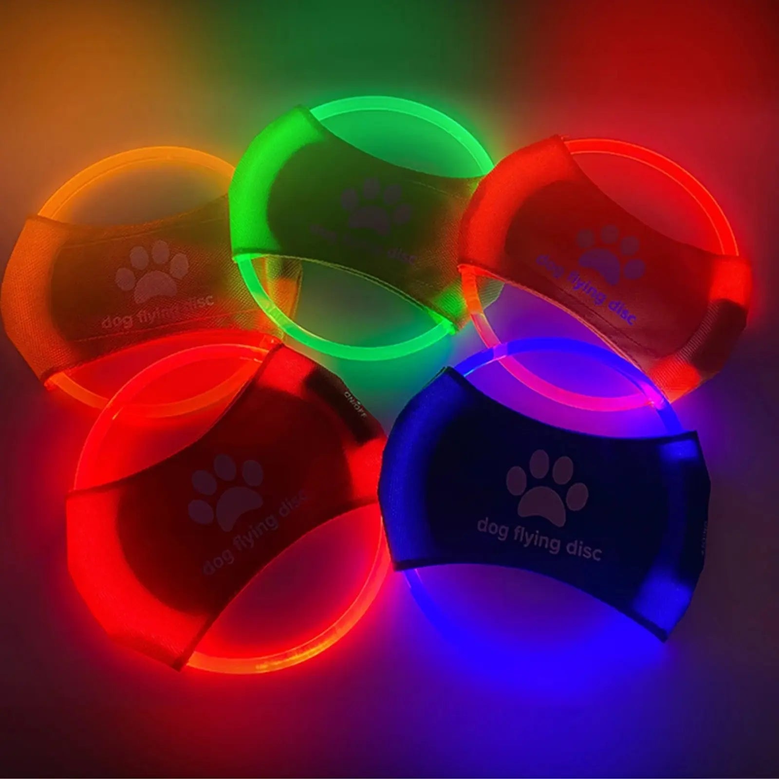 Multiple LookPaw™ rechargeable LED flying discs glowing in the dark
